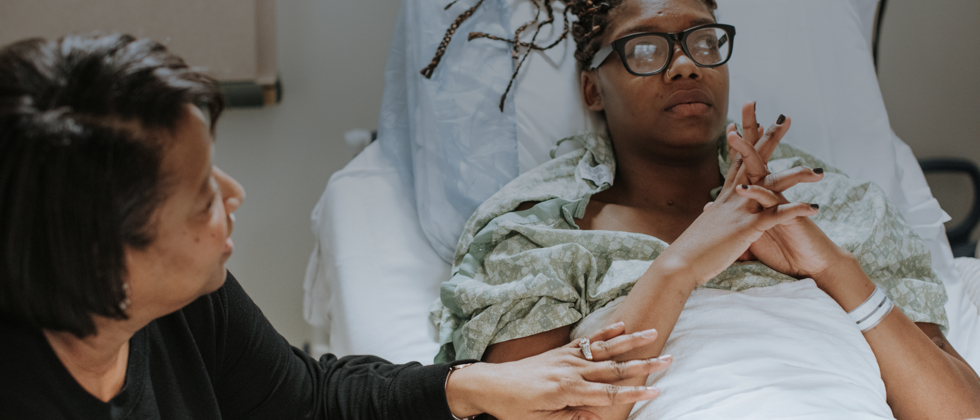 a woman sitting next to a woman in a hospital bed