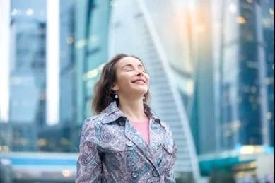 A woman standing in front of a city building.
