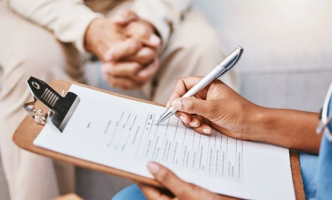 Krankenschwester oder Arzt schreibt auf einem Klemmbrett mit Stift eine Checkliste gemeinsam mit dem Patienten