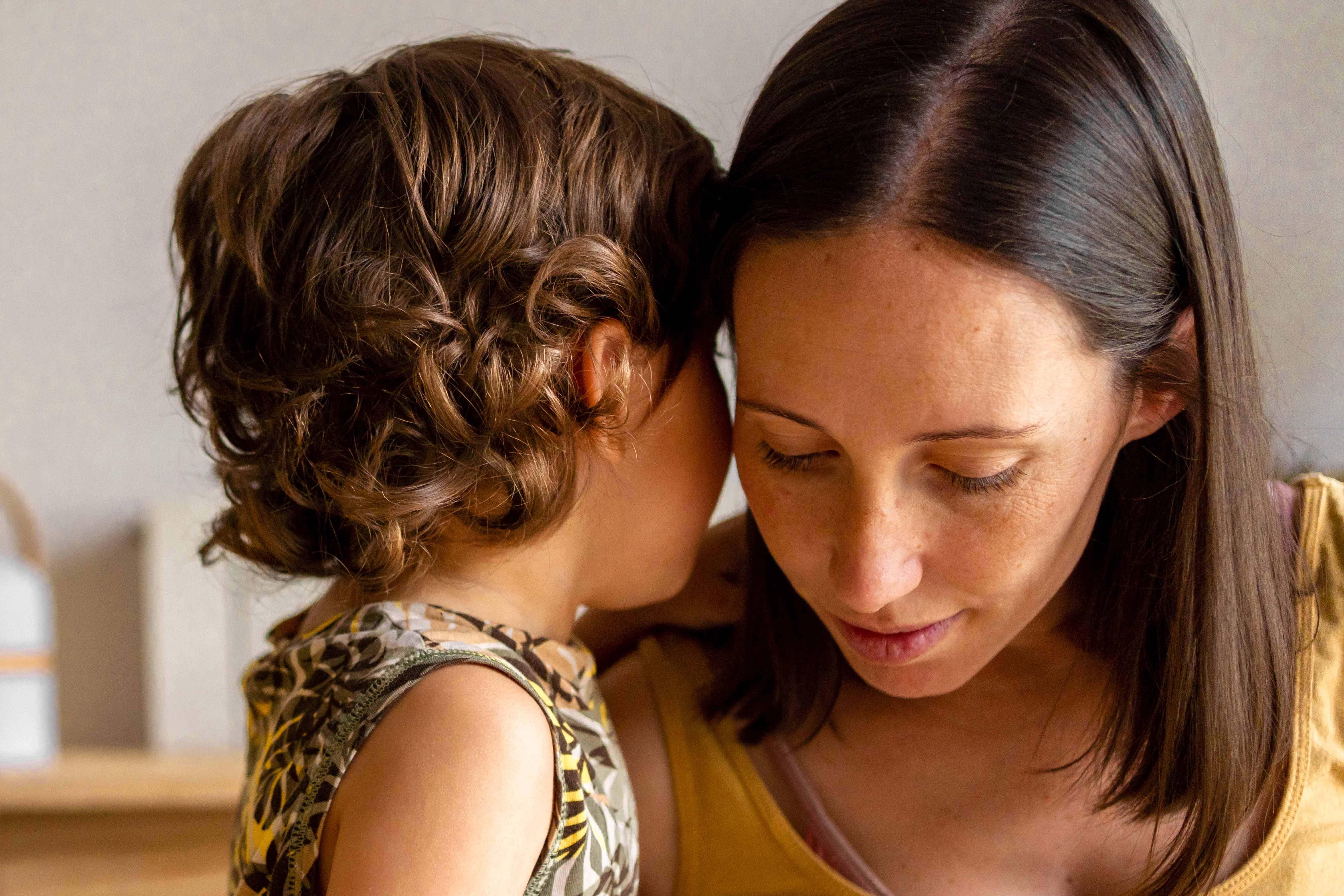 a child whispering into a woman's ear