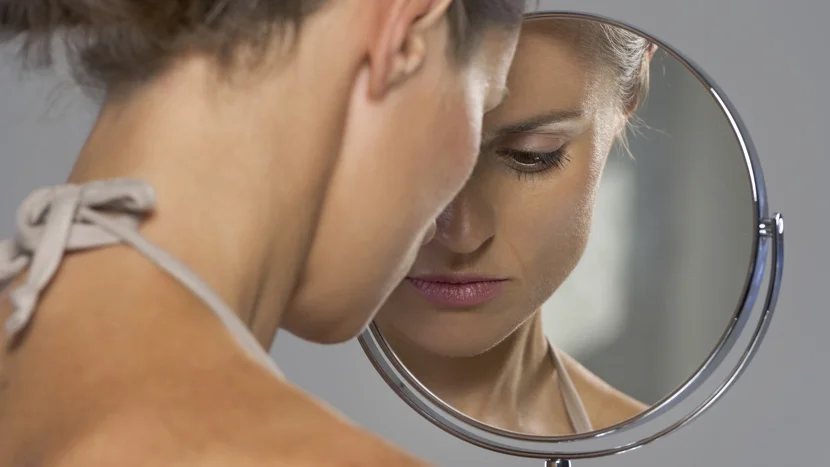 a woman looking at a mirror